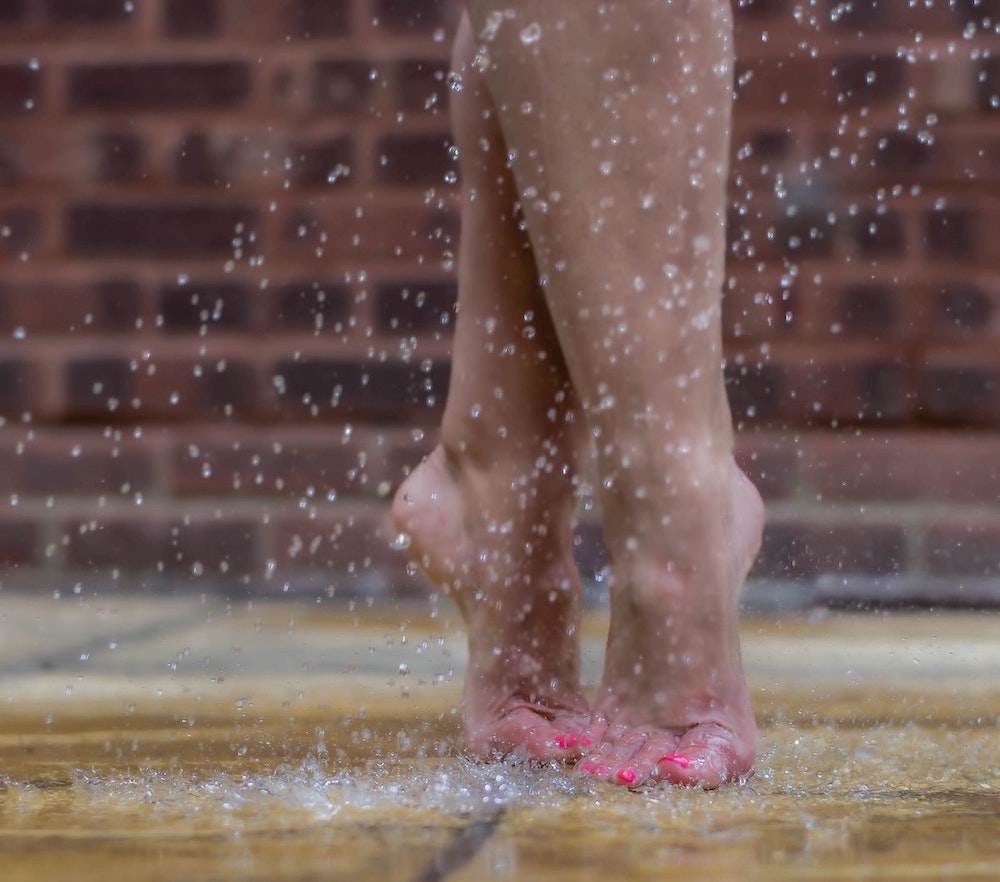 Dancer's feet in relevé fifth position with hot pink toe nail polish in the rain