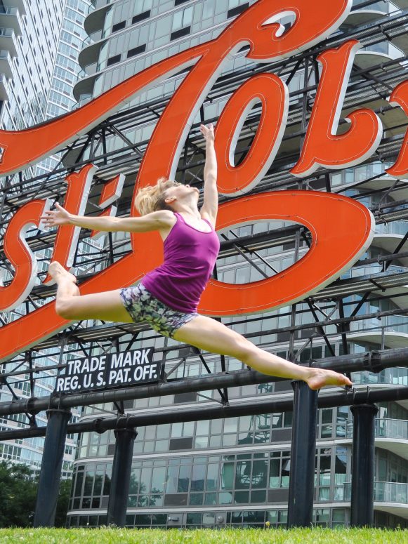 Heidi Friese owner of Move With HPA For Dancers doing grand jete in front of pepsi cola sign in long island city, NYC